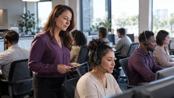 Contact center agents at workstations with a supervisor reviewing operations.