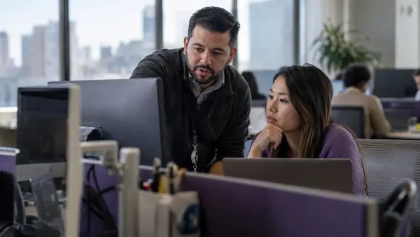 IT engineer helping a colleague with a business workstation.