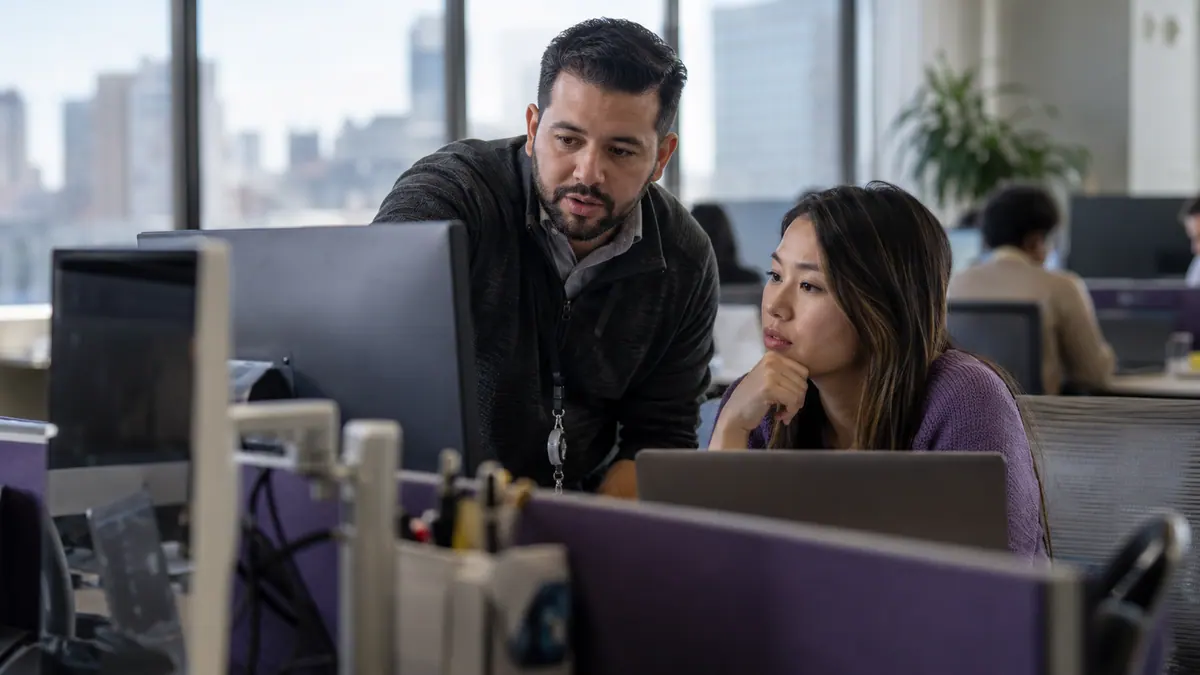IT engineer helping a colleague with a business workstation.